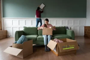 A happy couple using a checklist while unpacking boxes in their new Auckland home, following a guide to moving house.