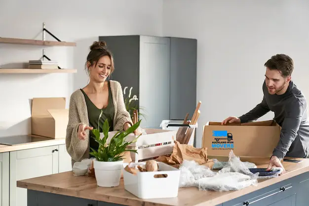 Essential kitchen packing supplies including boxes, bubble wrap, packing paper, and tape laid out on a kitchen floor.