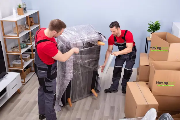 Two specialist apartment movers in Auckland carefully exiting a lift with a client's furniture, showcasing their expertise in high-rise moves.