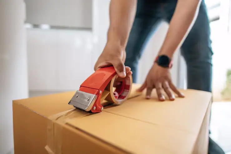 A man securely taping a sturdy moving box using professional techniques to save money on affordable movers Auckland.